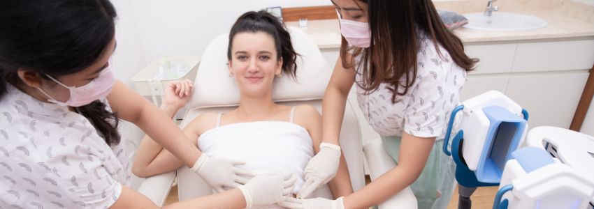 a woman having a breast lift treatment in bed with 2 staffs