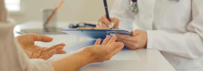 hands of a doctor and a patient with the doctor writing in a piece of paper
