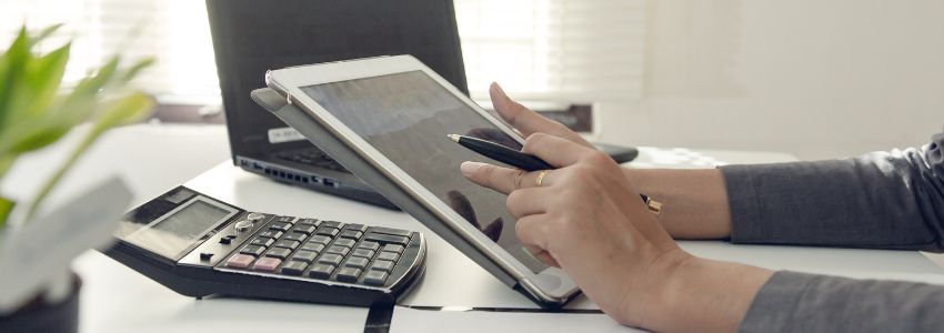 a table with a calculator with the hand of a man calculating the cost