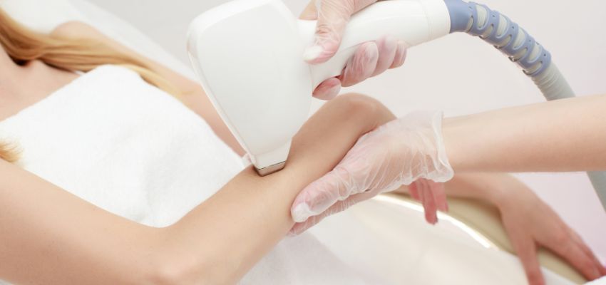 The woman is undergoing laser hair removal to remove the hair on her arms.