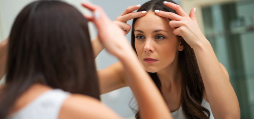 The woman checks her forehead for wrinkles.