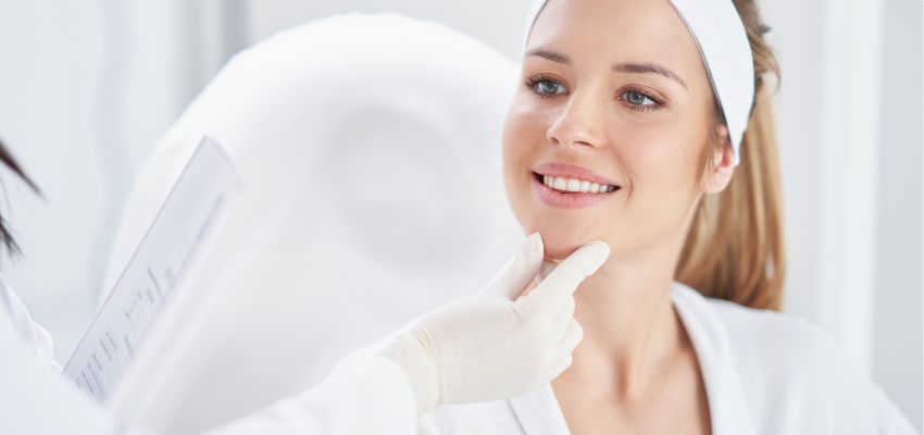 A woman receiving a facial evaluation by a professional, identifying potential botox injection sites.