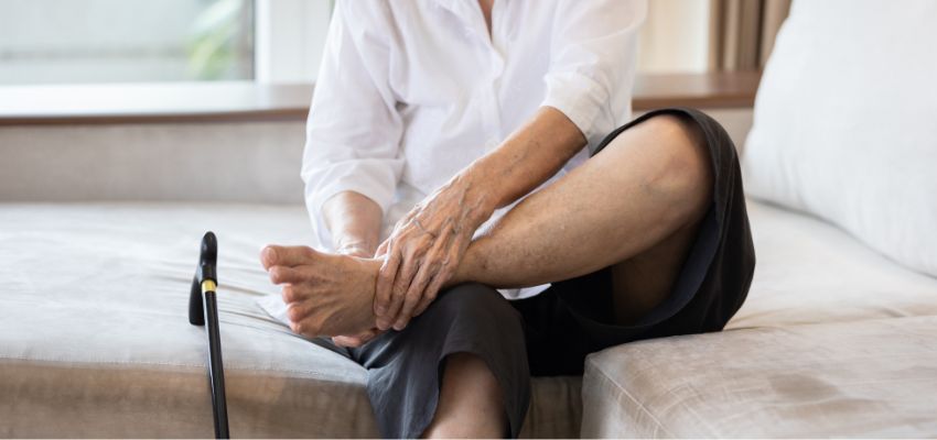 The older woman applies moisturizer to her feet to prevent dark ankles.
