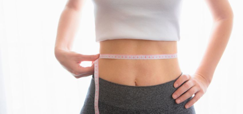 A woman measuring waist after undergoing several CoolSculpting sessions.
