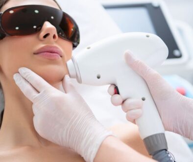Patient undergoing BBL halo laser treatment with protective eyewear while a specialist uses a laser device on her face.